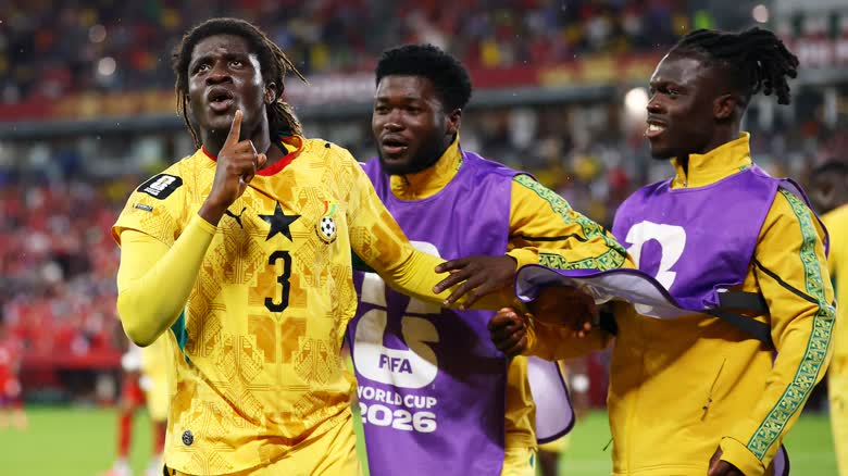 Ghanaian soccer players in bright yellow kits celebrate a goal.