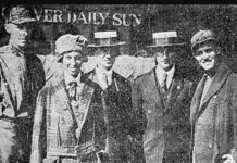 A news paper photo of five people posing in front of a newspaper office.