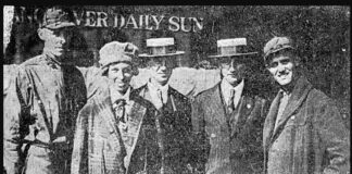 A news paper photo of five people posing in front of a newspaper office.
