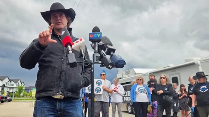 Corb Lund 在 Elections Alberta 辦公室外向傳媒發言，配合 Water Not Coal 請願被拒報道。