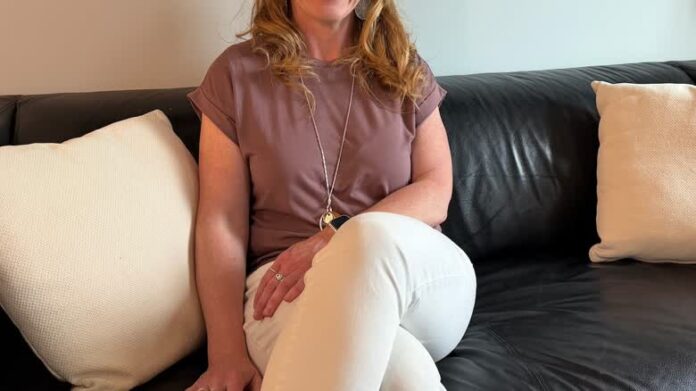 卡加利教師 Kristy Moore 站在住宅前，反映加拿大旅客以家居交換節省旅費。