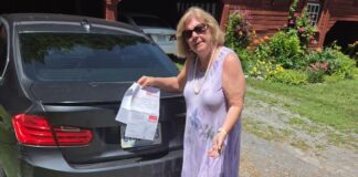 Nancy Griffin 手持停車罰單站在找回的車旁。