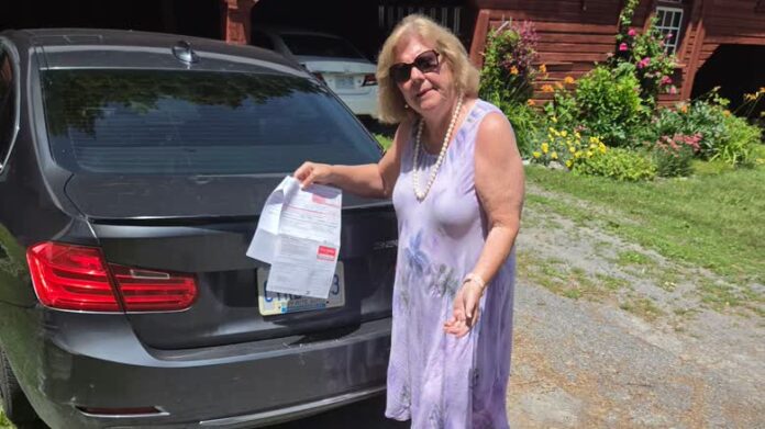 Nancy Griffin 手持停車罰單站在找回的車旁。