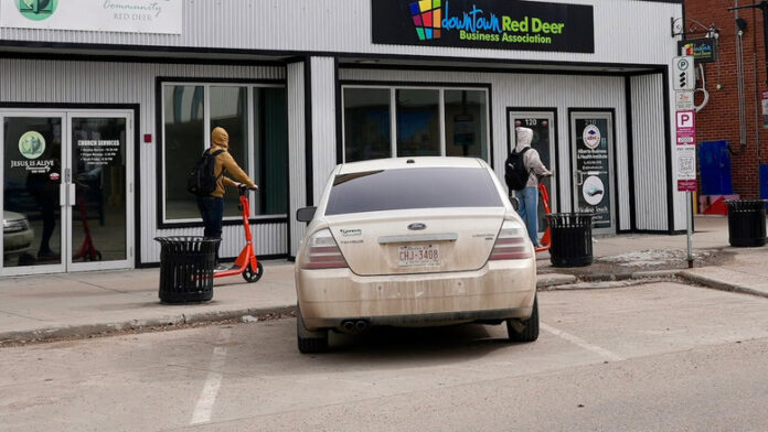 兩名人士在Red Deer市中心駕駛電動滑板車。