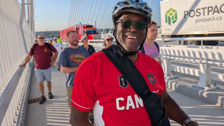 A man wearing a bike helmet and smiling warmly as he stands next to his bike.