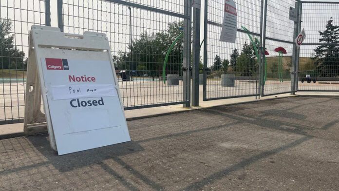 A closure sign in front of a fenced off splash pad