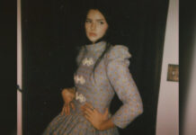 A young woman with dark hair and a long dress poses for the camera in a promotional photo.