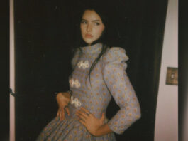 A young woman with dark hair and a long dress poses for the camera in a promotional photo.