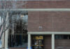 A red brick building with large glass windows with snow outside.