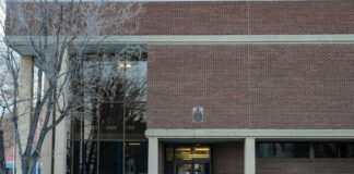 A red brick building with large glass windows with snow outside.