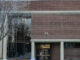 A red brick building with large glass windows with snow outside.
