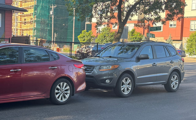 一輛灰色汽車在愛民頓住宅街道停泊，與前車距離很近。