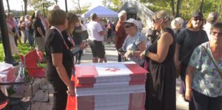義工在愛民頓 Hawrelak Park 派發 Forever Canadian 草坪牌