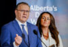 A man and a woman speak at a podium.