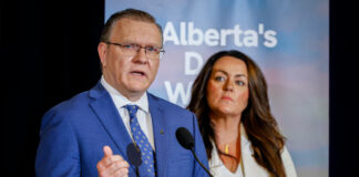 A man and a woman speak at a podium.