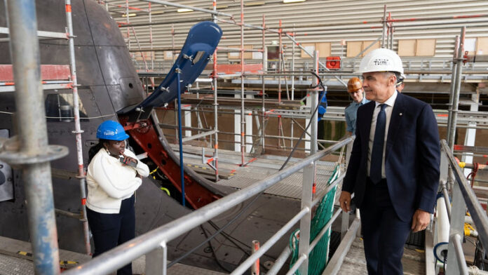 Prime Minister Mark Carney looks over a 212A class submarine under maintenance as he tours the ThyssenKrupp Marine Systems submarine-building facility in Kiel, Germany, in August 2025. (Christinne Muschi/The Canadian Press)