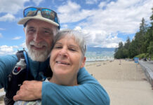卑詩夫婦徒步八年逾1.5萬公里 將抵橫加步道終點 A smiling couple embraces while taking a selfie beside the seawall and beach in Vancouver’s Stanley Park.