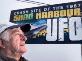A man is shown in front of a billboard that says 'Crash site of the 1967 Shag Harbour UFO.'