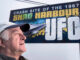 A man is shown in front of a billboard that says 'Crash site of the 1967 Shag Harbour UFO.'