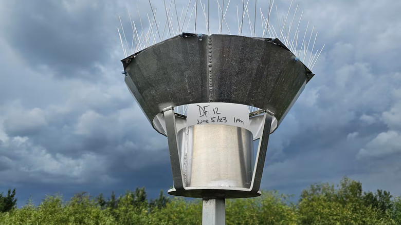 A large bucket sampler covered in spikes sits on a pole