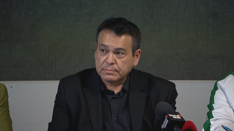 A man in a black suit with a mic in front of him.