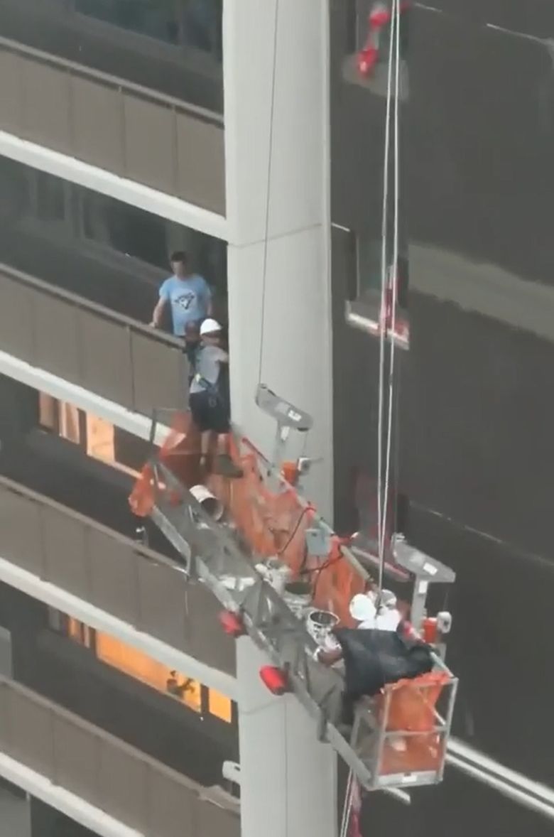 強風下約克維爾大廈外懸吊棚架上的工人