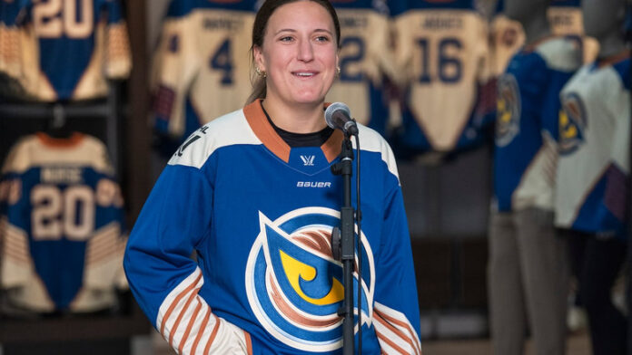 The Vancouver Goldeneyes' Jenn Gardiner is seen with the team's new jersey for the upcoming 2026-27 season on Wednesday. (Hunter Soo/CBC) 圖片來源：Hunter Soo/CBC